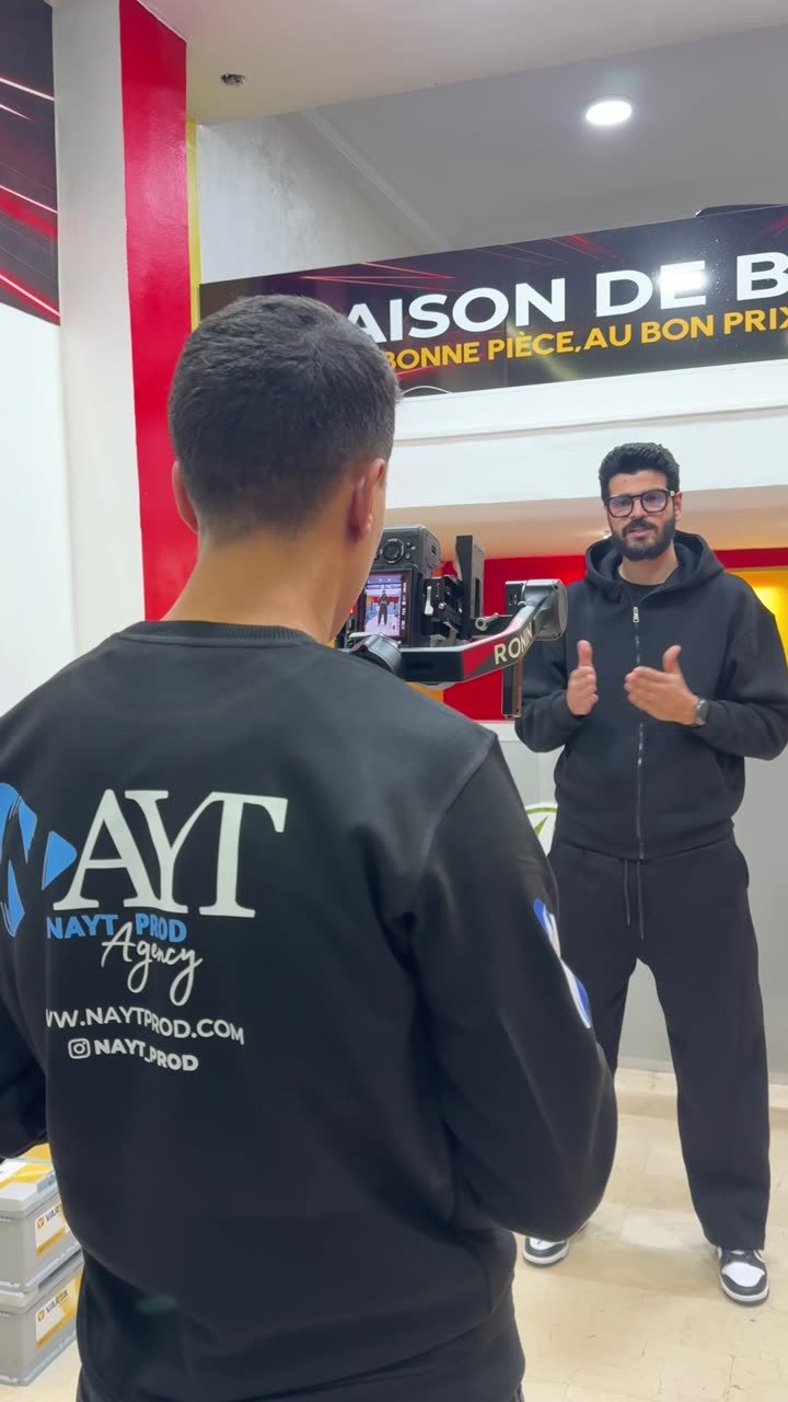 Deux membres de l'équipe en sweat NAYT dans un magasin, enseigne du point de vente en arrière-plan.