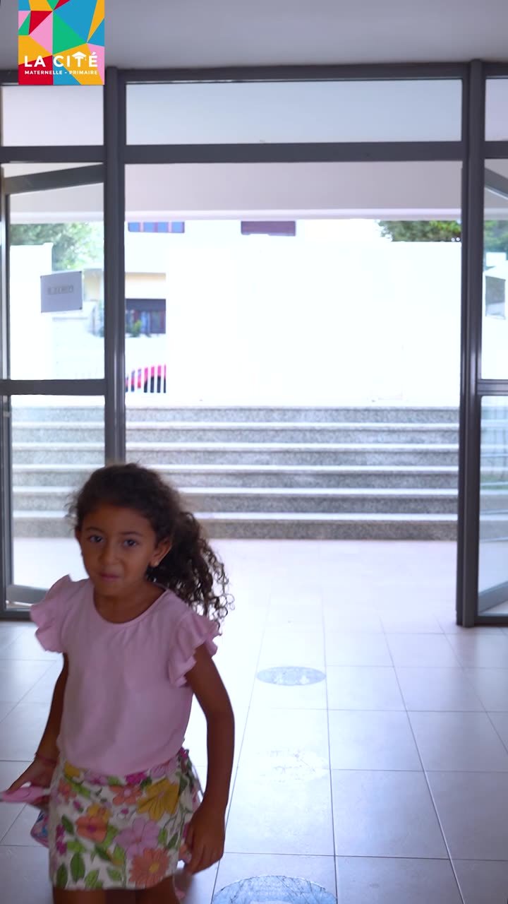Élève arrivant devant l'entrée vitrée d'un établissement scolaire, logo La Cité en surimpression.
