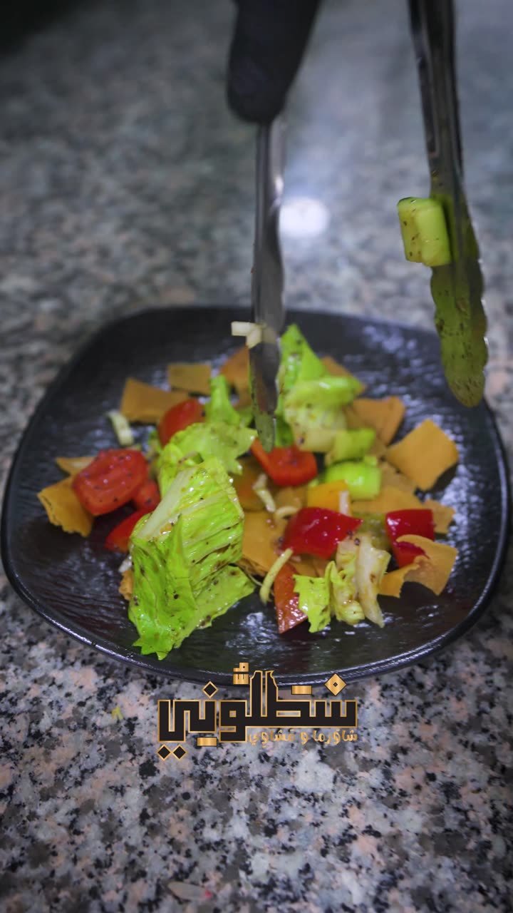 Assiette de salade composée en gros plan, dressage en cours à la pince, logo Stalloni en surimpression.